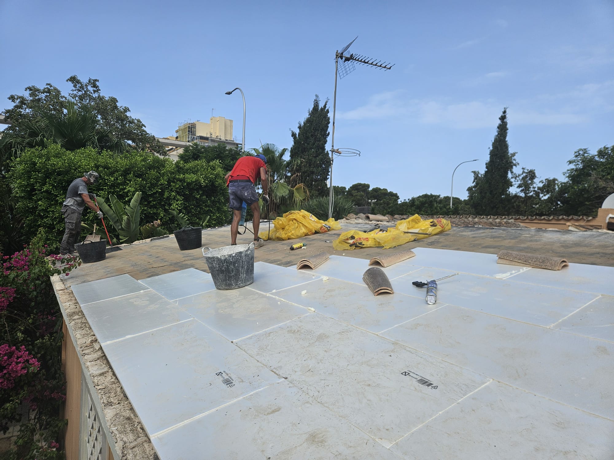 Workers laying rigid insulation boards during flat roof renovation in Mallorca