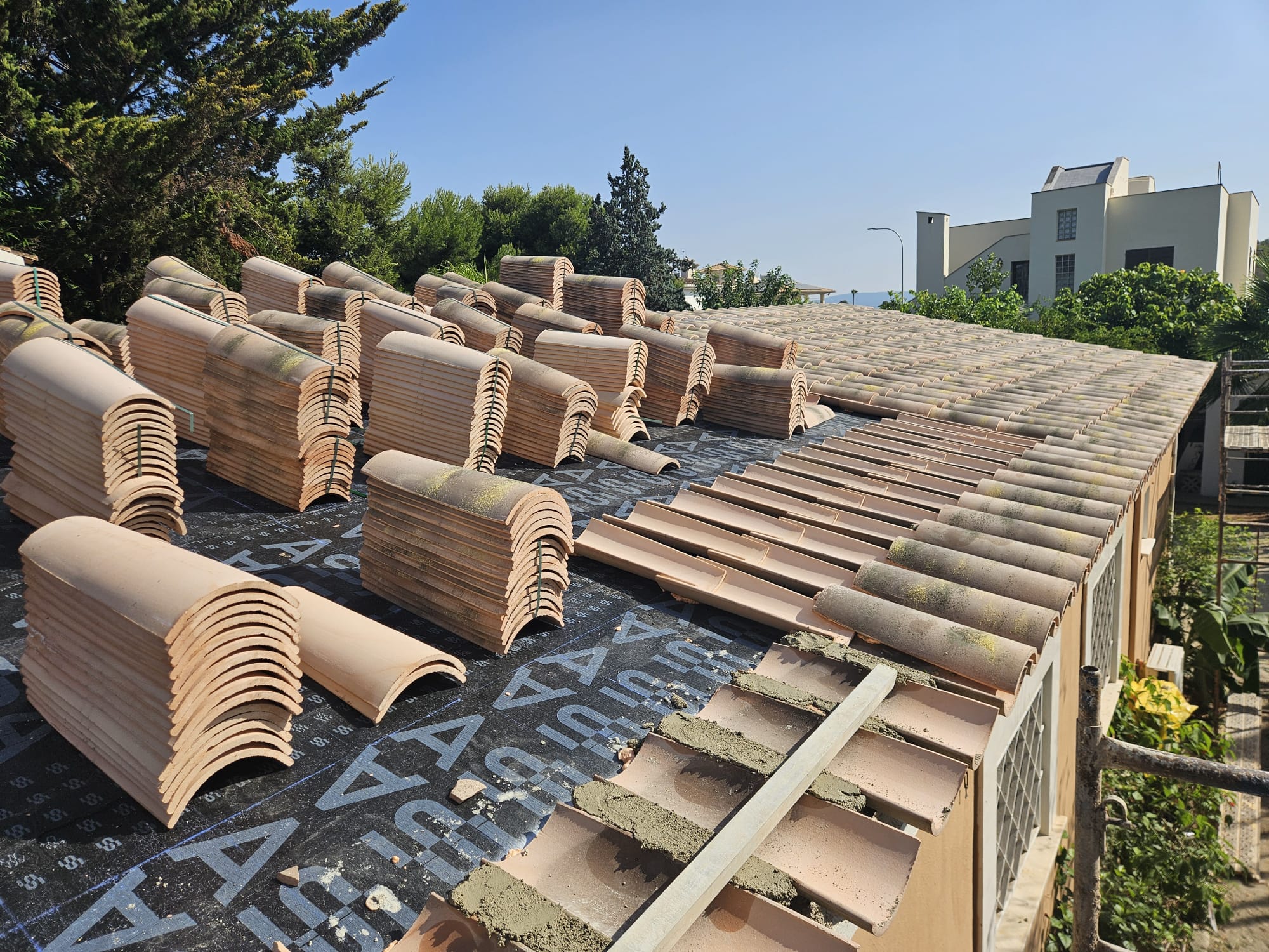 New terracotta tiles being arranged and laid on renovated roof in Mallorca